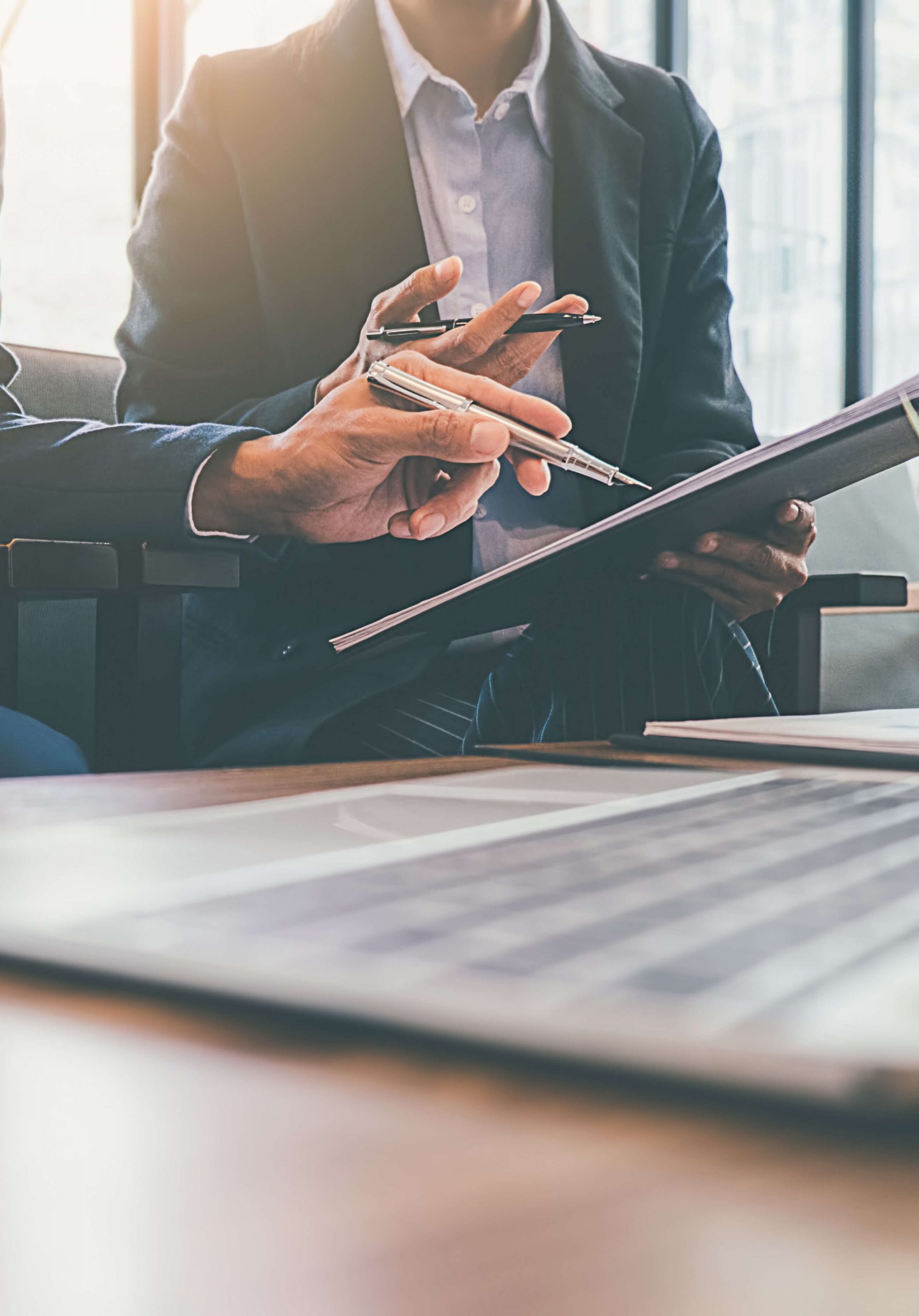 AdobeStock_251299506 copy Close-up of business professionals reviewing documents and using a laptop.